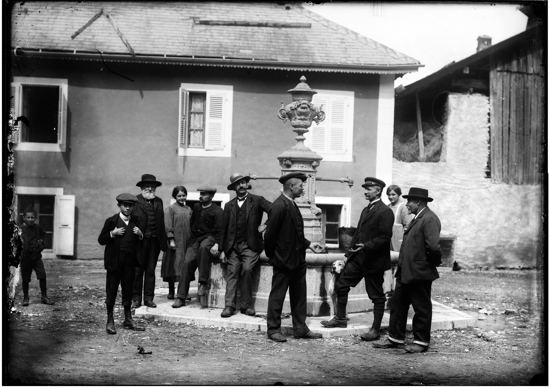 Vie sociale : sur la place "de l'ancienne Mairie", près de l fontaine alors intacte, ces messieurs  prennent la pose et discutent : sortie du Conseil municipal peut-être ?